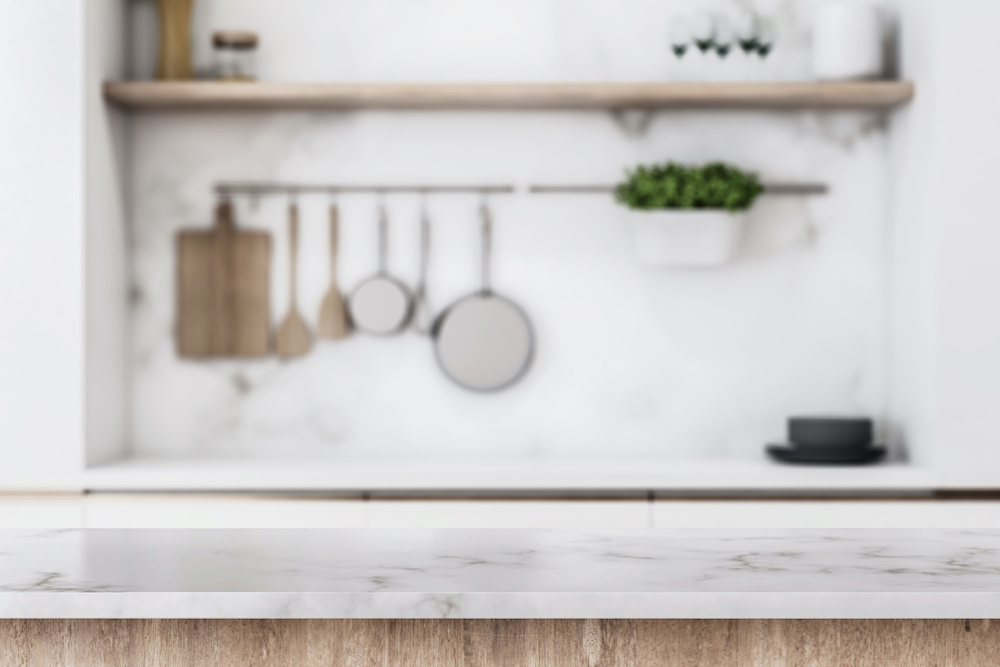 Stylish marble tabletop on wooden platform with copyspace for your logo at blurry kitchen utensils and dishes on light wall background. 3D rendering, mock up